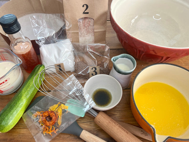 Kitchen items including a whisk, bowls, and a bottle on a wooden surface.